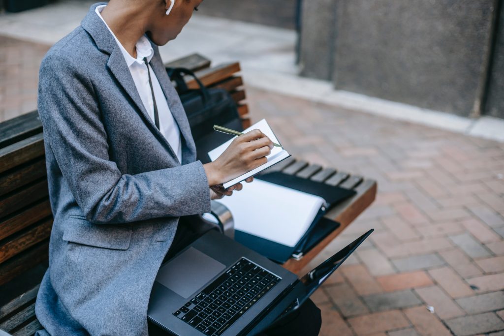 A project manager sitting on the bench writing down some notes.