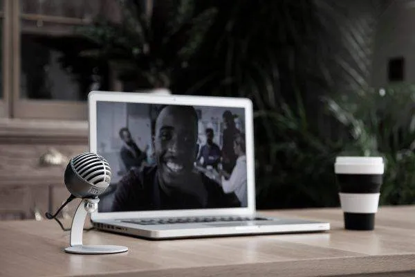 A microphone next to a computer and a cup of coffee